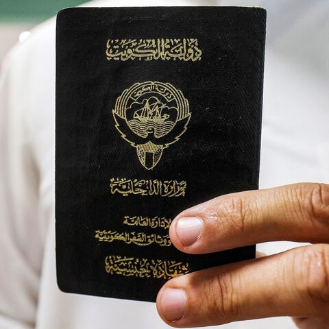 A voter holds his proof of Kuwaiti citizenship upon arriving at a polling station during parliamentary elections in Kuwait City on June 6, 2023. 