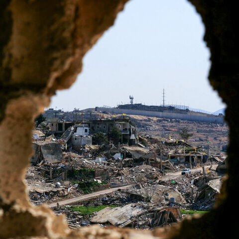 A vehicle drives past buildings destroyed in Israeli strikes during the latest war, near the border wall in the southern Lebanese village of Ramia on March 5, 2025. Lebanese official media said two people were wounded on March 5 when Israeli drones attacked a vehicle in the south, a day after a deadly raid and despite a November 27 ceasefire. (Photo by Mahmoud ZAYYAT / AFP) (Photo by MAHMOUD ZAYYAT/AFP via Getty Images)