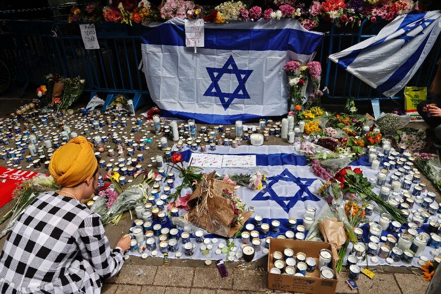 Israelis light candles at the site of the Tel Aviv shooting that has killed three men