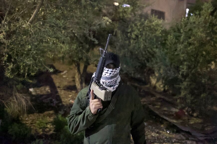 A masked spokesperson of the Al-Aqsa Martyr's Brigades, a faction affiliated to the Fateh movement, is pictured holding a M16 assault rifle in the West Bank town of Jenin on April 12