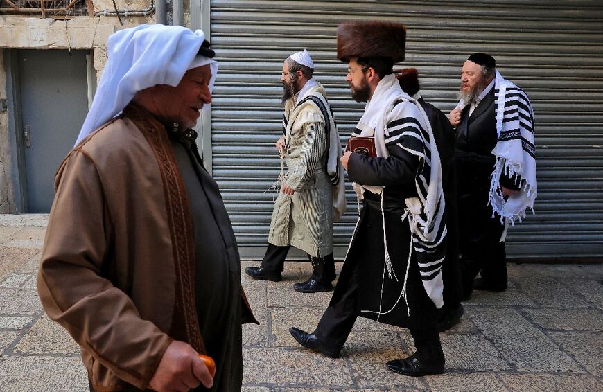 A Palestinian man walks past ultra-Orthodox Jews in Jerusalem's Old City