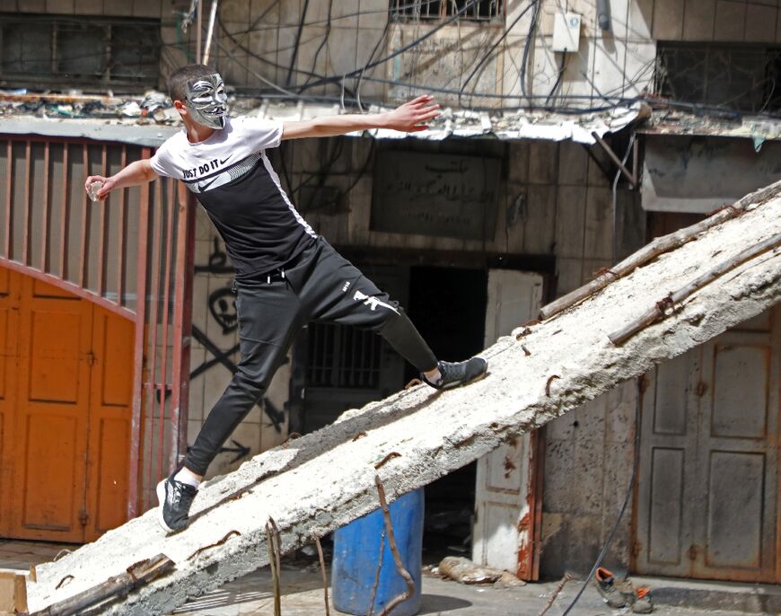 A Palestinian demonstrator hurls rocks amid clashes with Israeli security forces in Hebron city in the occupied West Bank, on April 1, 2022