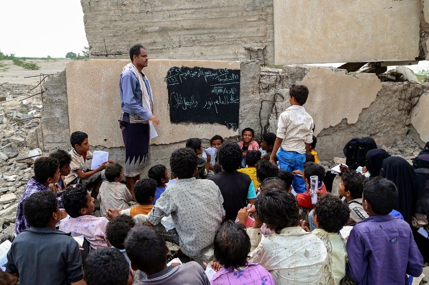 Children attend an outdoor class amid the rubble of their destroyed school on the first day of the new academic year in Yemen's western province of Hodeida on August 21
