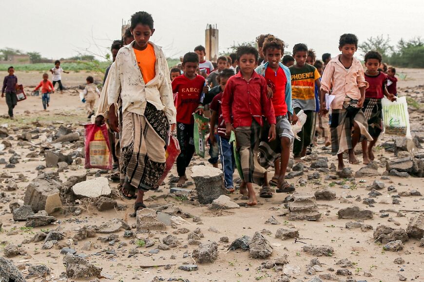 Children make their way across rubble as they arrive for an outdoor class in the western province of Hodeida