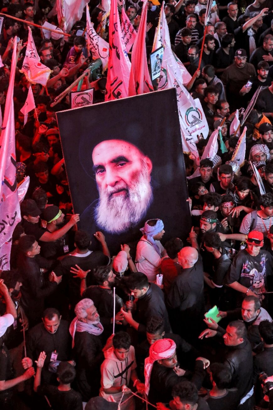 Shiite Muslim devotees raise a picture of Iraq's top Shiite cleric Grand Ayatollah Ali al-Sistani as they gather in Iraq's central holy shrine city of Karbala on September 16