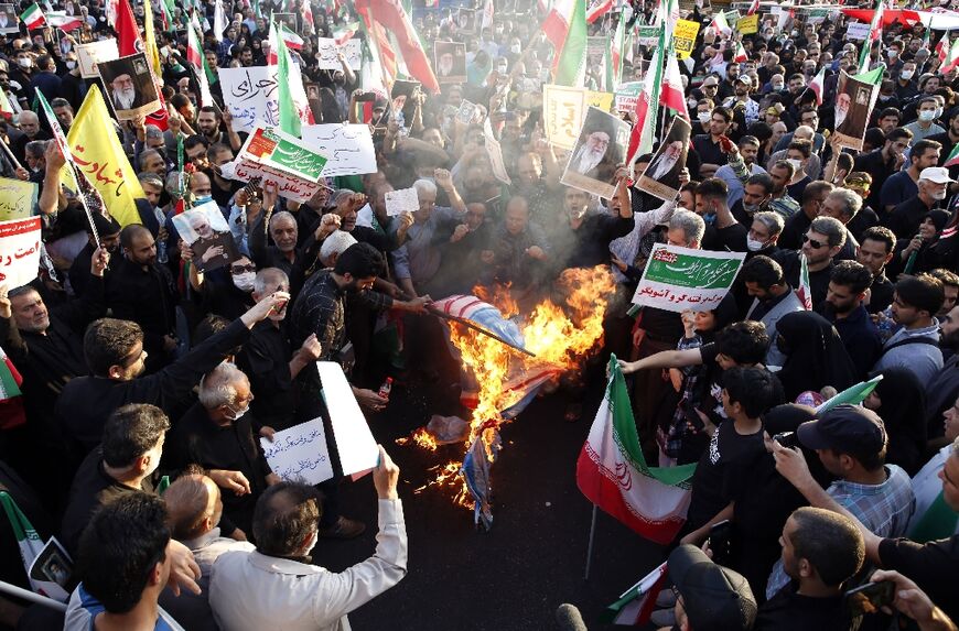 Iranian pro-government protesters burn flags of the US, Israel and Britain during a rally against the recent anti-government protests in Iran, in Tehran, on September 25