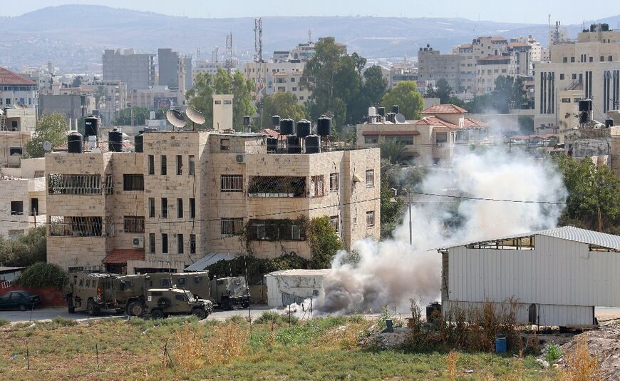 Smoke billows around Israeli security forces vehicles during a reported operation in Jenin city in the occupied West Bank