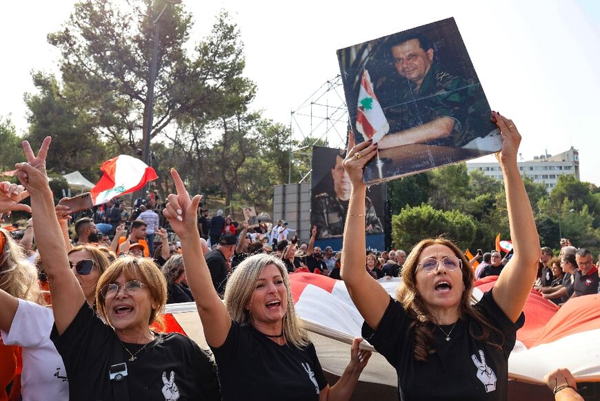 Supporters of Lebanon's outgoing President Michel Aoun hold up his picture and unfurl a large national flag in front of the presidential palace