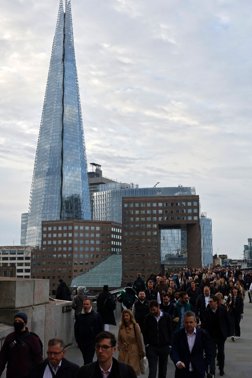 Pedestrians on their way to work, cross London Bridge, with the Qatari-owned Shard behind, in central London
