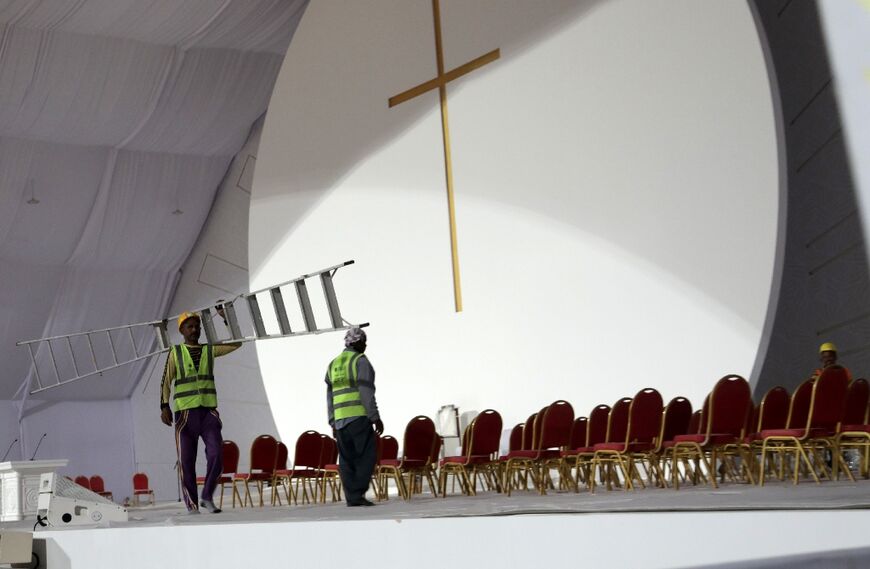 Workers add finishing touches on stage at the Bahrain National Stadium, including a giant gold cross above the pope's chair