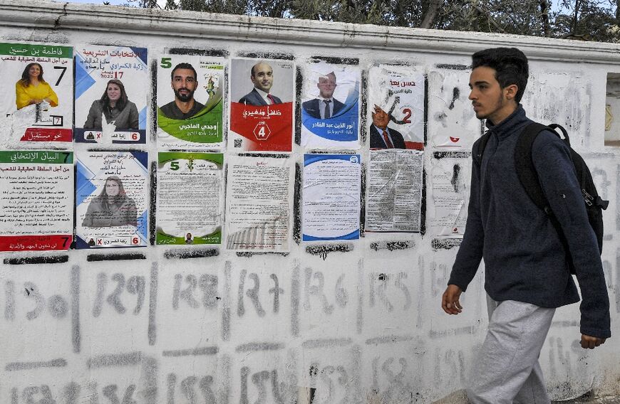A youth walks past electoral posters for candidates who ran in the Tunisian national election 