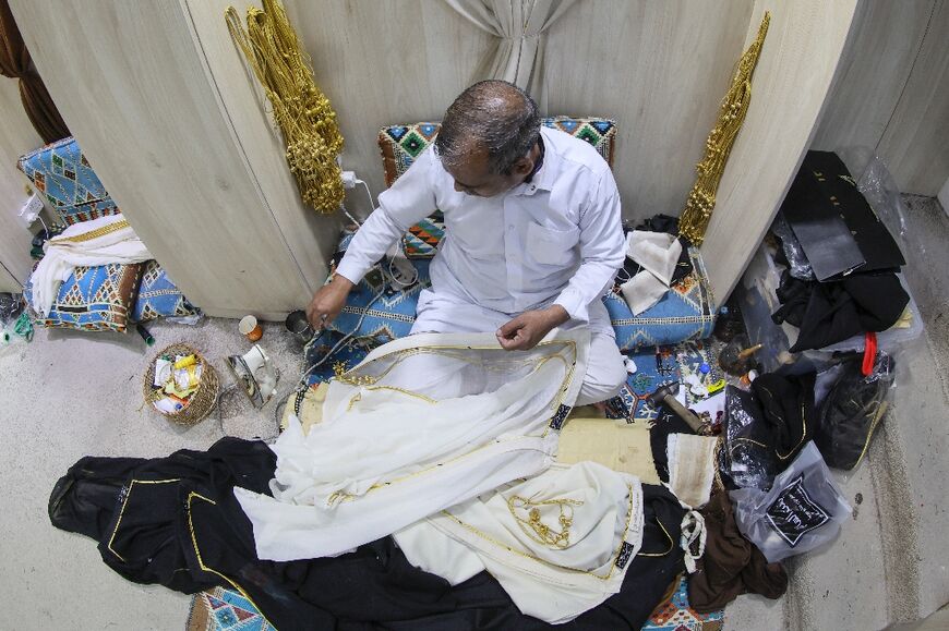 A Qatari man works on a traditional black and gold Arab bisht cloak at the Al Salim store in Doha's Souq Waqif 