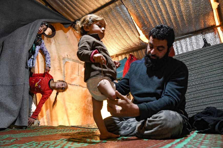A resident of an internally displaced persons camp with his daughter in Syria's rebel-held northwestern Idlib province, near the Bab al-Hawa border crossing