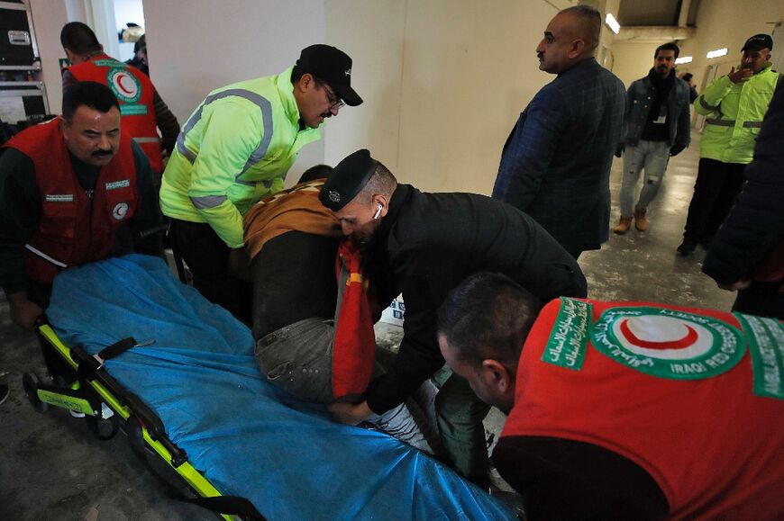 Iraqi paramedics tend to crush victims after the stampede outside the International Stadium in Basra