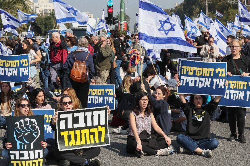 Israeli protesters lift national flags and placards as they rally in Tel Aviv against controversial legal reforms being pushed by the government