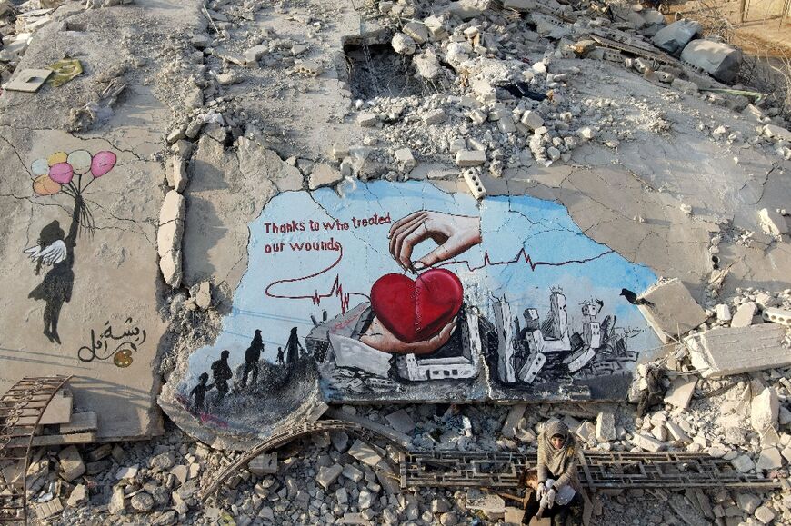 Artwork to thank aid efforts is painted on the rubble of a building that collapsed during the February 6 earthquake in the Syrian rebel-held town of Jindayris 