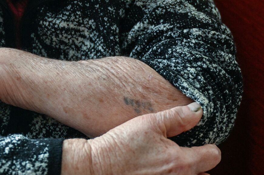 Holocaust survivor Naki Bega shows the concentration camp tattoo on her arm