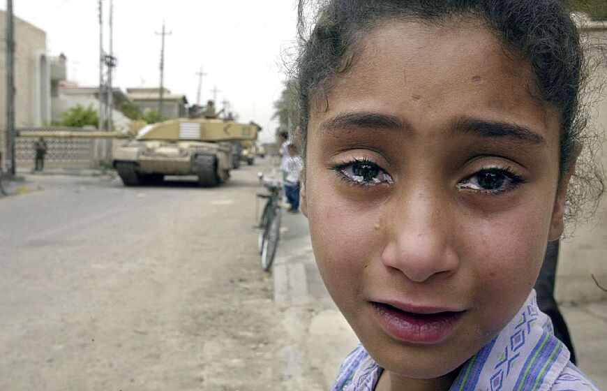 A young Iraqi girl cries as a British Challenger tank is seen moving through Basra, in this file photo from April 8, 2003 