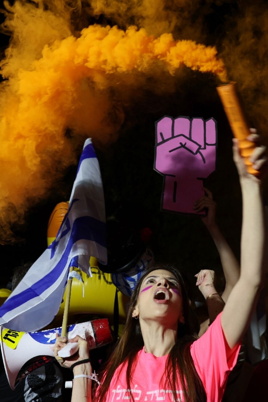 A demonstrator lights a smoke flare during a protest against the Israeli government's controversial judicial reform bill in Tel Aviv on March 11, 2023