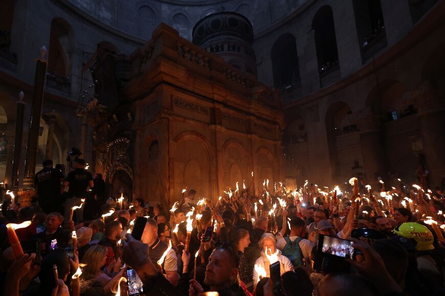 Orthodox Christians gather with lit candles around the Edicule