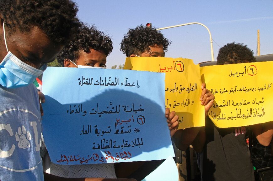 Protesters hold up signs stating their demands from Sudan's military leadership