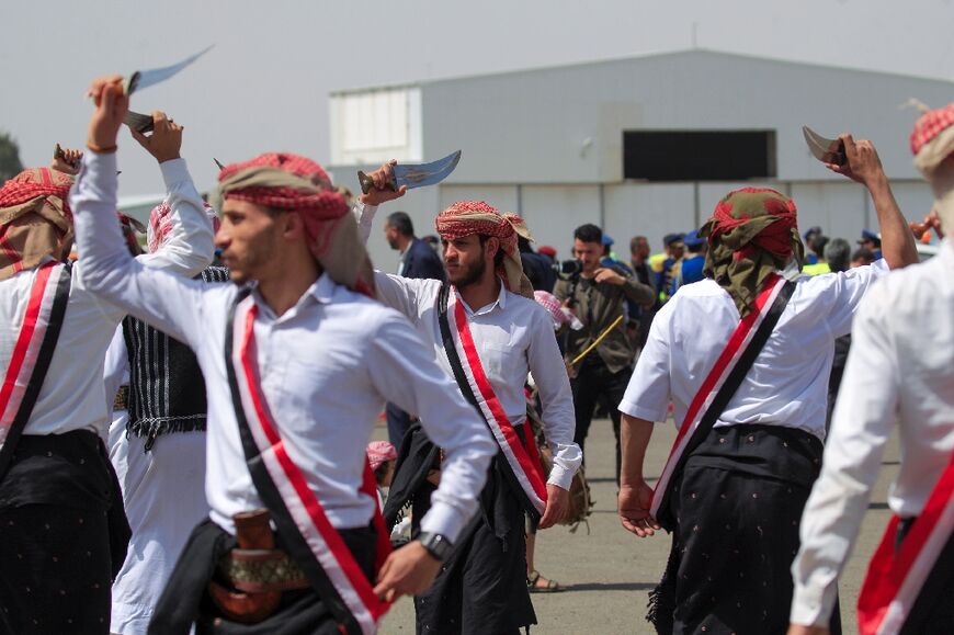 Huthi fighters stage a ceremonial dance with swords to greet released detainees at Sanaa airport