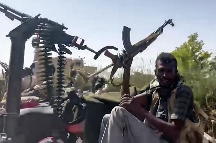 In this image from video footage released by the Sudanese paramilitary Rapid Support Forces, a fighter waves an assault rifle while riding in the back of a pickup truck mounted with a turret in the East Nile district of greater Khartoum