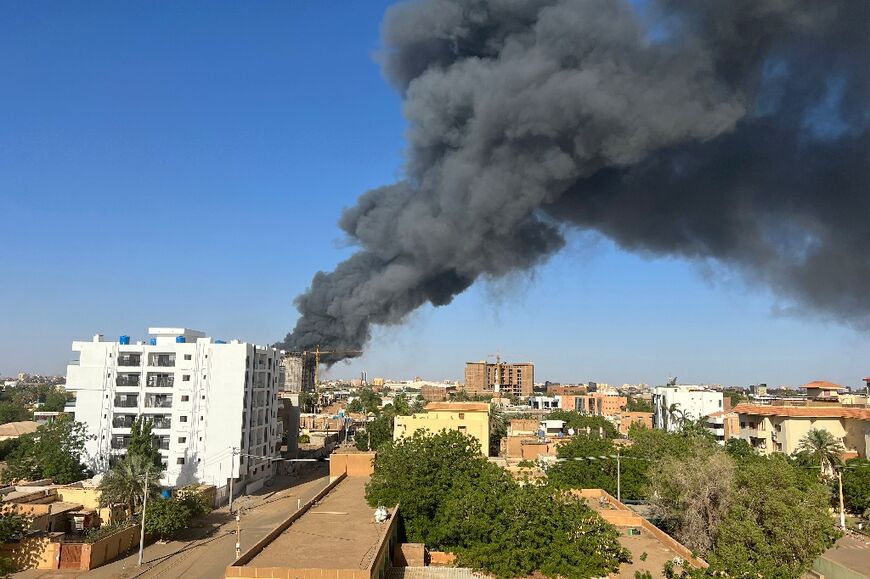 A column of smoke rises behind buildings near the airport area in Khartoum 