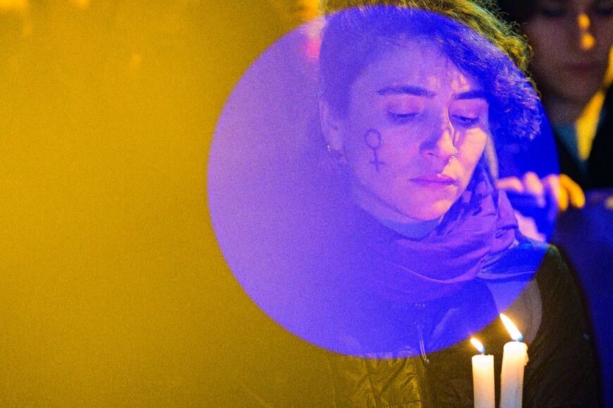 A woman lighten by camera light holds candles during a march to Taksim Square to mark the International Women's Day in Istanbul on March 8, 2023.