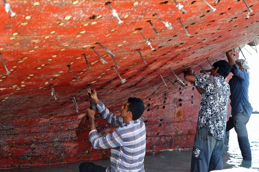 Workers restore a traditional wooden lenj boat on Iran's Qeshm island in the Gulf