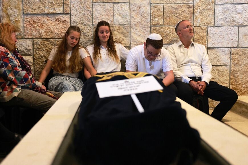 Widower Leo Dee and his three surviving children attend the April funeral of his wife Lucy, who died of her injuries three days after the West Bank shooting which killed two of her daughters