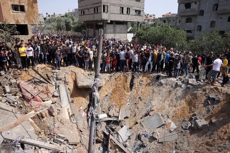 Onlookers gather around a crater caused by an Israeli air strike in Beit Lahia on May 12