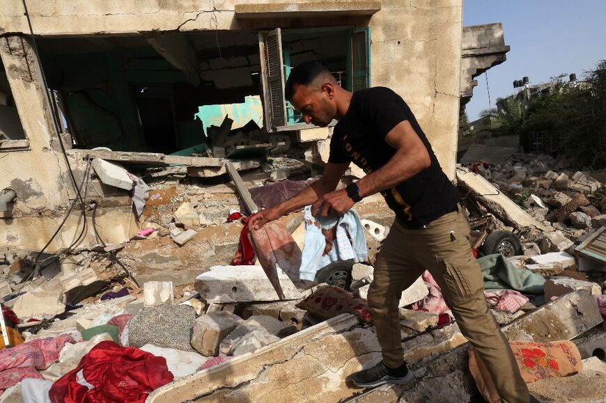 A man retrieves blood-stained clothes from the rubble of the house of Ahmed Abu Deka, the Palestinian deputy of the commander of a rocket launch unit killed by Israel