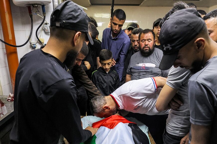 Palestinian mourners gather by the body of Abdullah Abu Hamdan, 24, at a morgue in Balata camp