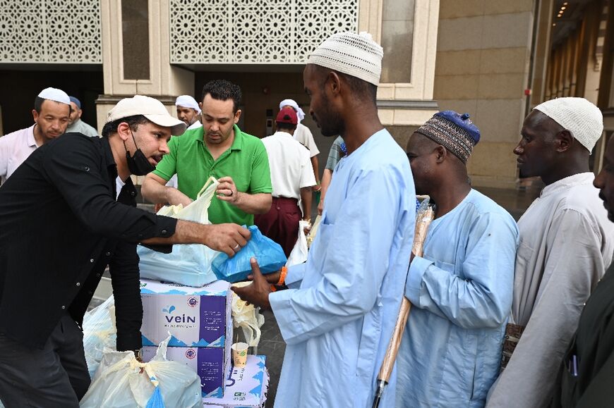 Across the holy city of Mecca, young men distribute free meals consisting of rice, chicken or meat to pilgrims who line up in long queues