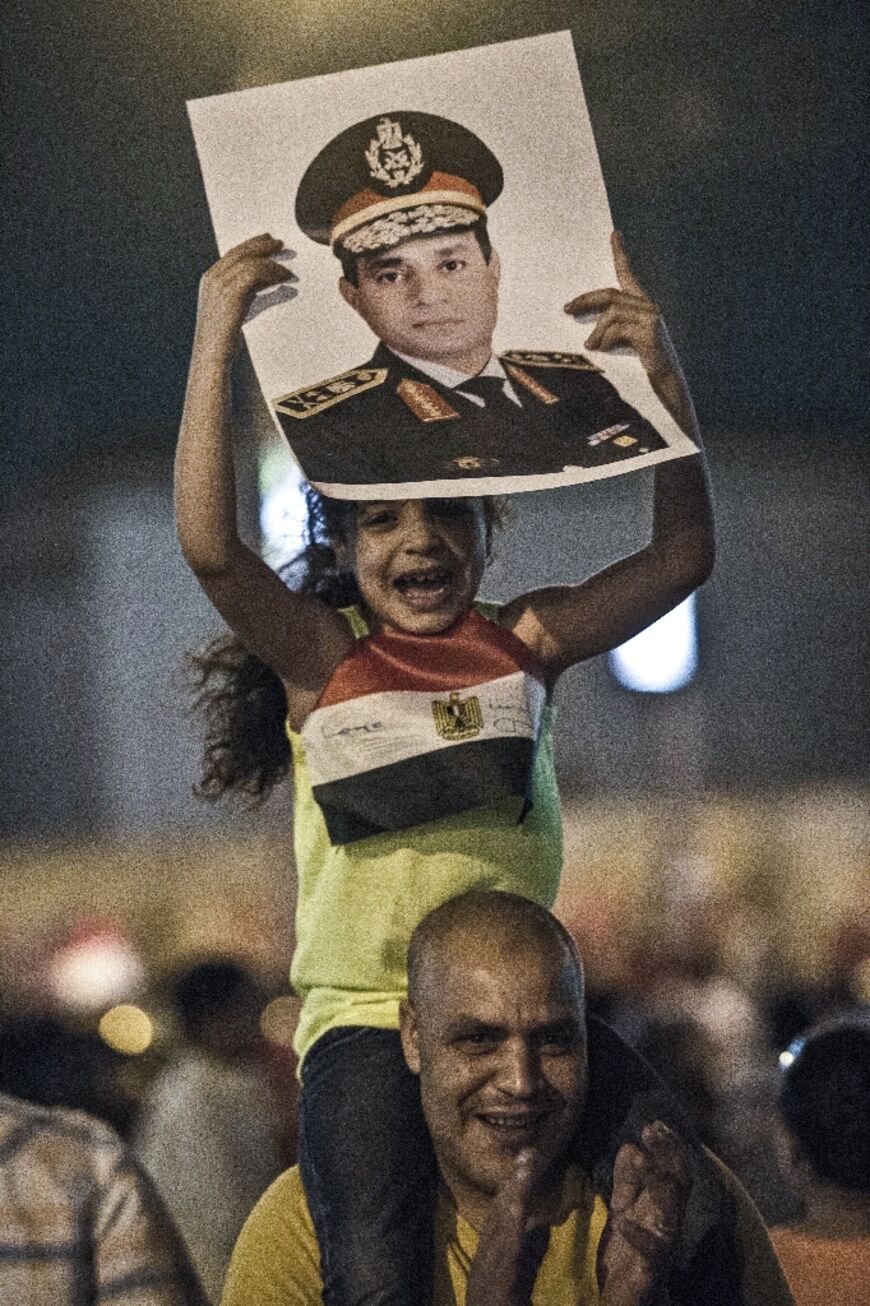 A man carries his daughter on his shoulders on July 1, 2013 as she holds a picture of then army chief Fattah al-Sisi during a protest
