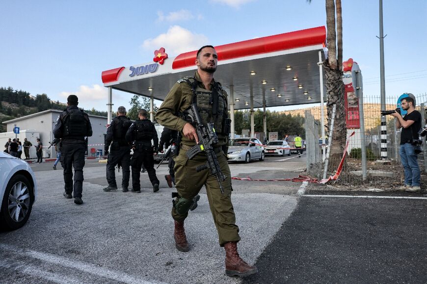 An Israeli soldier walks out of a petrol station at the scene of the shooting that left four dead
