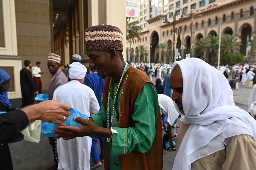 Pilgrims receive food packages offered as part of traditional hospitality by the residents of Mecca