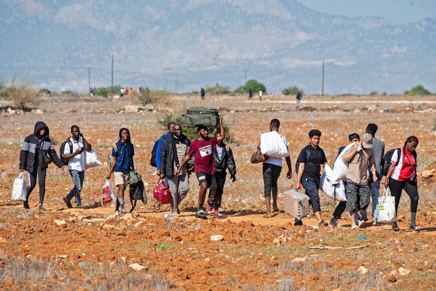 Migrants leave the Pournara camp, the main reception centre for migrants in Cyprus, after reported unrest at the crowded facility on October 28, 2022 in Kokkinotrimithia on the edge of the capital Nicosia