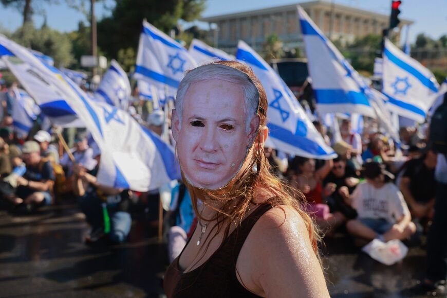 A demonstrator wearing a mask depicting Israeli Prime Minister Benjamin Netanyahu takes part in a sit-in at the entrance to Israel's parliament, just before a vote on the judicial overhaul plans