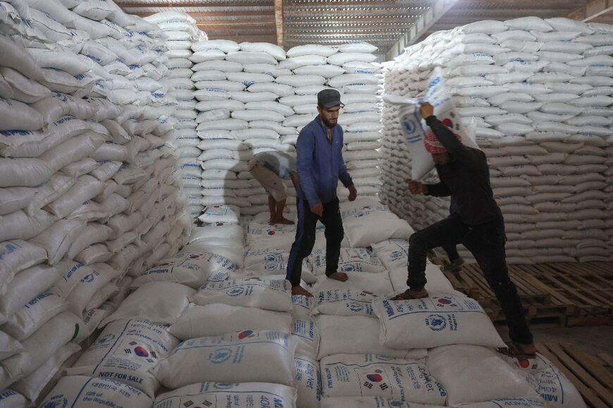 Workers unload bags of food aid at a warehouse near the Syrian Bab al-Hawa border crossing with Turkey, on July 10, 2023