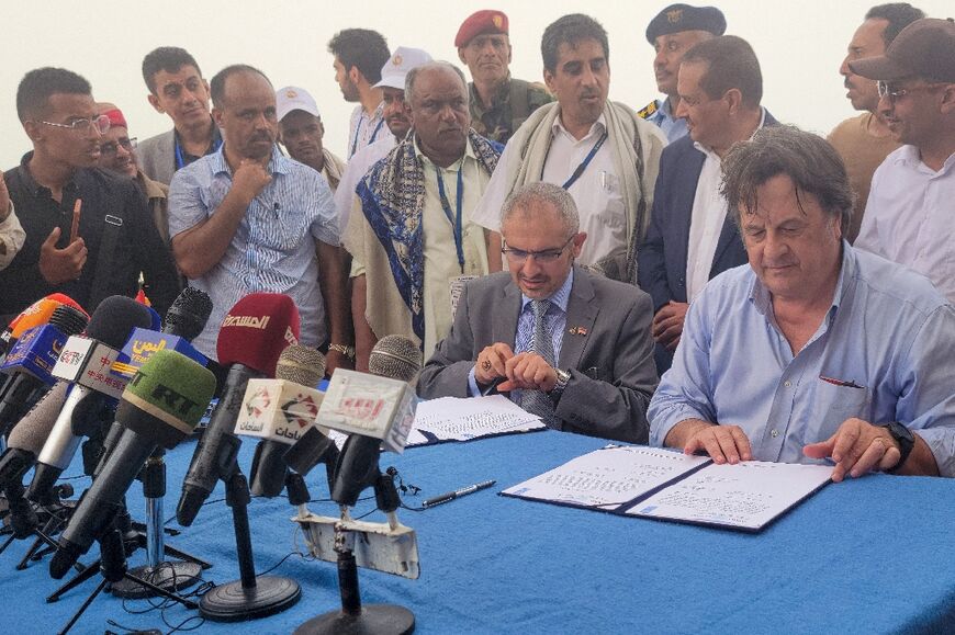 UN resident coordinator for Yemen David Gressly (R) and Edrees al-Shami (2nd-R), the Huthi-appointed executive general manager of SEPOC, sign documents on board the UN-owned Nautica vessel off the coast of Yemen's western port of Hodeida