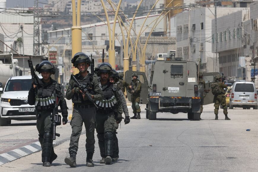 Members of Israeli security forces block a road leading to the site of the attack