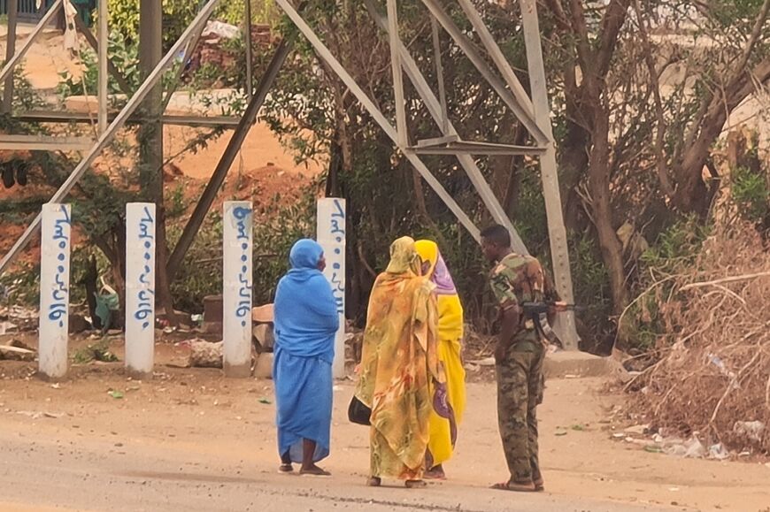 A soldier talks to women on an empty street in Khartoum