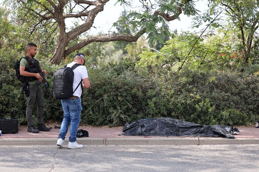 Israeli security men near the covered body of the gunman