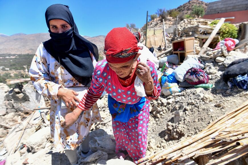 Women walk on the rubble of homes in the rubble of Imoulas village 