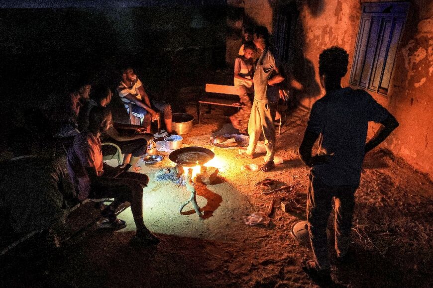 People displaced by Sudan's war cook on a bonfire at a school transformed into a shelter in Sudan's northern border town of Wadi Halfa, near Egypt 