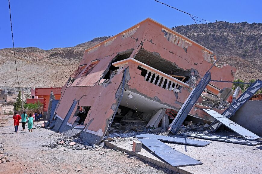 People walk past a destroyed house near Amizmiz in Morocco's worst-hit province of al-Haouz 