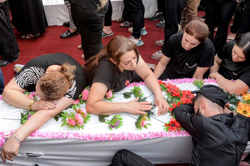A family mourns over a coffin containing one of the at least 100 people killed