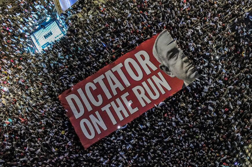 Demonstrators unfurl a giant banner against Israeli Prime Minister Benjamin Netanyahu during a Tel Aviv rally against the judicial overhaul plan on September 23, 2023